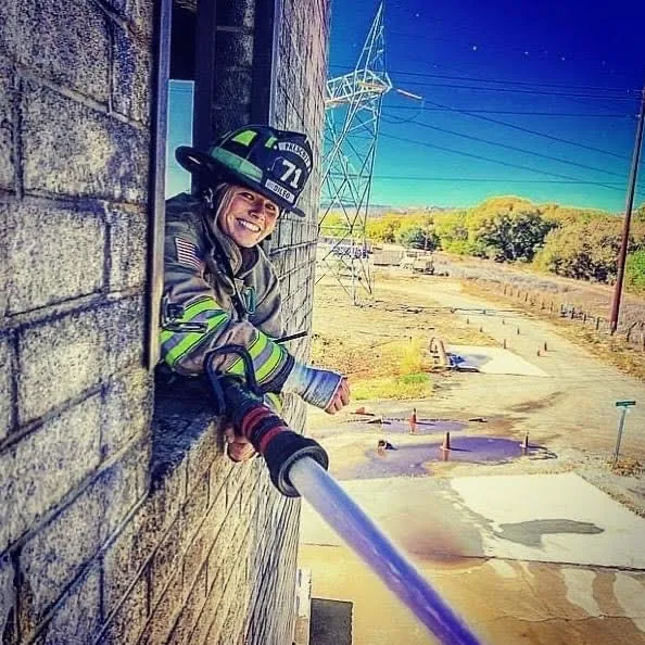 Prescott Firefighter in building with hose smiling.