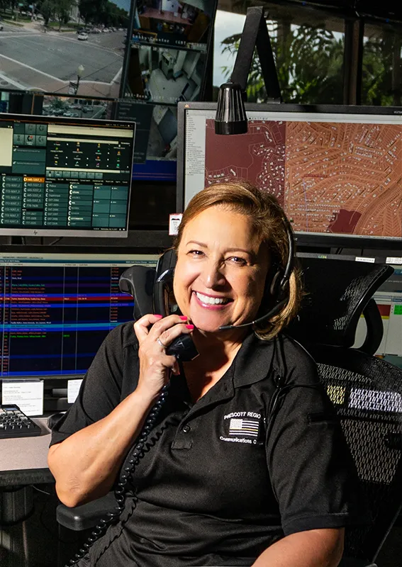 Prescott Regional Communications Center PRCC operator smiling at camera on the phone.